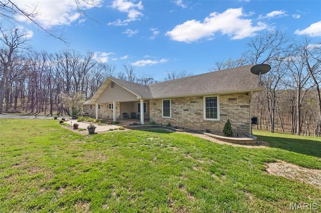 view of front of home featuring brick siding, a front lawn, and a patio