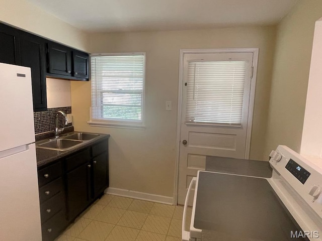 212 S Marguerite, Ferguson, MO 63135 - kitchen with freestanding refrigerator, washer / dryer, a sink, dark cabinetry, and baseboards