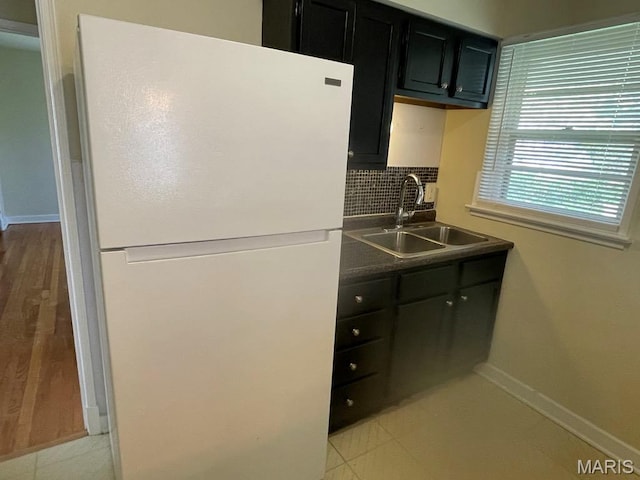 212 S Marguerite, Ferguson, MO 63135 - kitchen featuring freestanding refrigerator, a sink, dark cabinetry, baseboards, and backsplash