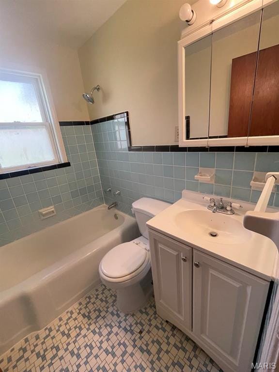 212 S Marguerite, Ferguson, MO 63135 - bathroom with washtub / shower combination, toilet, vanity, tile walls, and a wainscoted wall