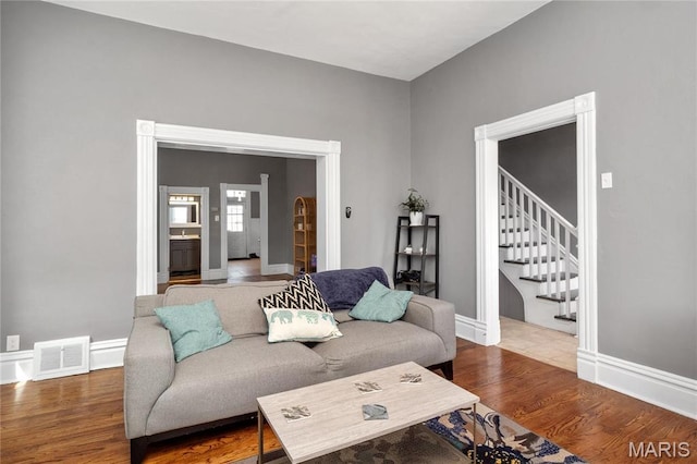 living room with wood finished floors, stairway, and baseboards