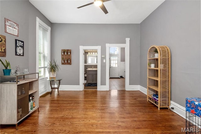 living area with ceiling fan, light wood-type flooring, and baseboards