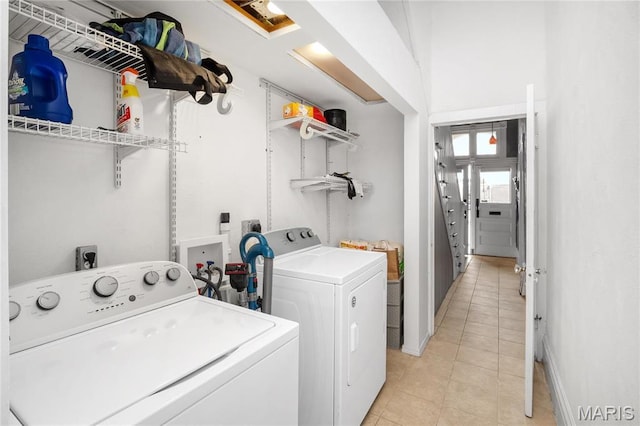 laundry room with washing machine and dryer, light tile patterned flooring, and baseboards