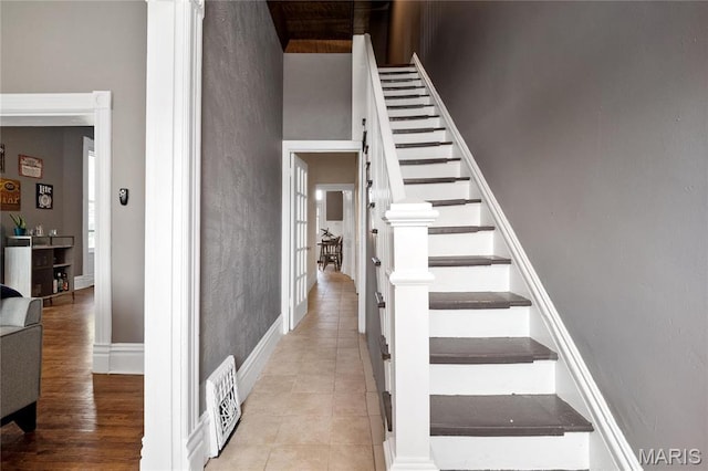 stairway with baseboards, a towering ceiling, and tile patterned flooring