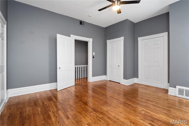 unfurnished bedroom featuring wood finished floors, baseboards, a ceiling fan, and a closet