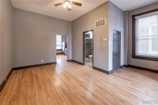 spare room with a ceiling fan, light wood-style floors, and baseboards