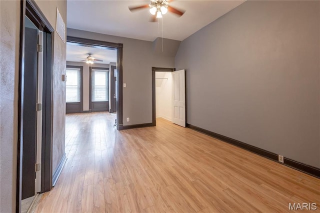 unfurnished bedroom with light wood-type flooring, baseboards, vaulted ceiling, and a ceiling fan