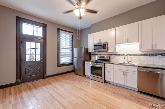 kitchen featuring appliances with stainless steel finishes, a sink, a ceiling fan, tasteful backsplash, and white cabinets