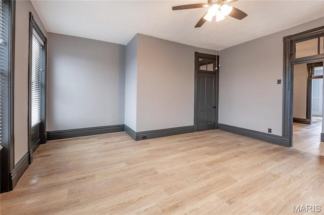 spare room with ceiling fan, light wood-style flooring, and baseboards