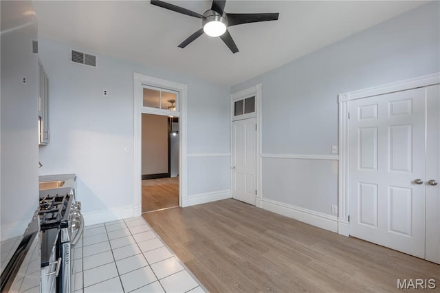 unfurnished dining area featuring ceiling fan, light wood-style floors, and baseboards