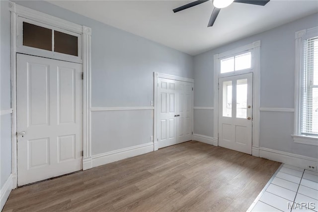 entrance foyer featuring light wood-style flooring, ceiling fan, healthy amount of natural light, and baseboards