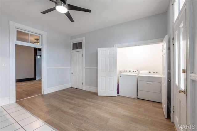 clothes washing area with separate washer and dryer, a ceiling fan, light wood-type flooring, and baseboards