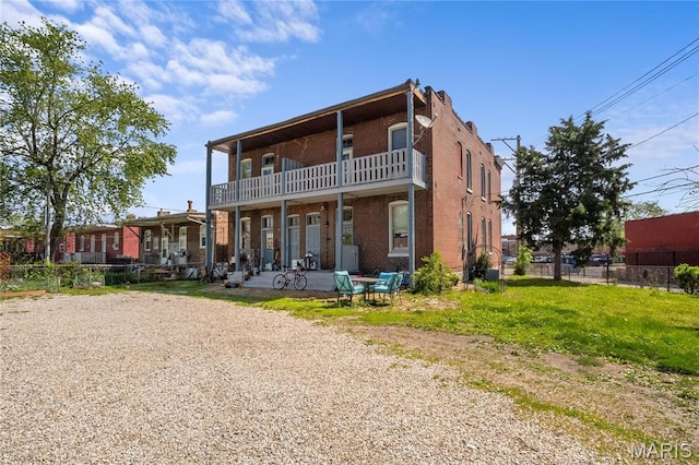 back of house featuring a balcony and brick siding