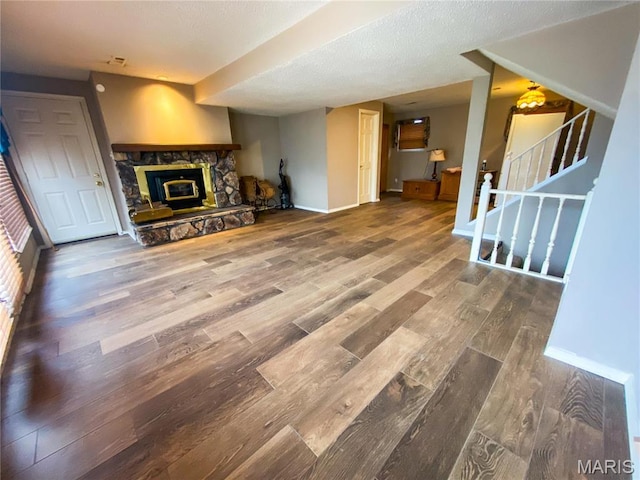 19113 Bent Oak Dr, Warrenton, MO 63383 - unfurnished living room featuring wood finished floors, a stone fireplace, stairway, and a textured ceiling