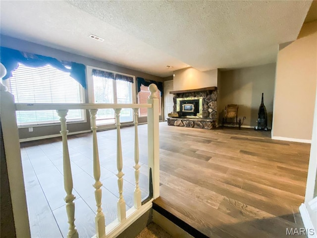 19113 Bent Oak Dr, Warrenton, MO 63383 - unfurnished living room featuring a textured ceiling, wood finished floors, and a stone fireplace