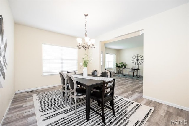 dining area with a chandelier, light wood-style floors, and baseboards