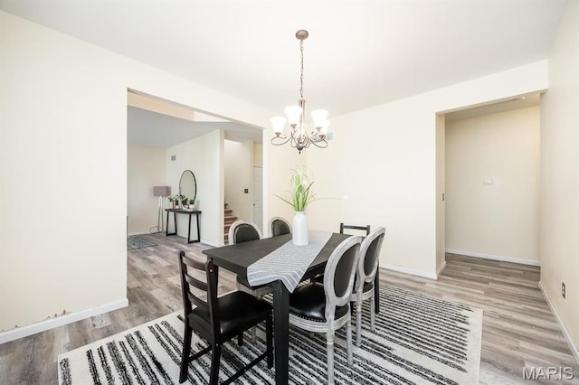 dining room featuring light wood-style flooring, a chandelier, and baseboards