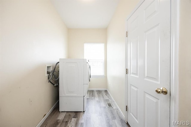 clothes washing area featuring washer / dryer, baseboards, and light wood-style flooring