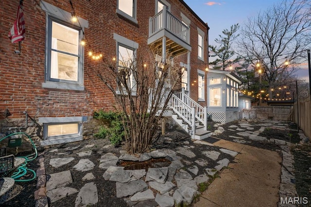 921 Morrison Ave, Saint Louis, MO 63104 - exterior entry at dusk with brick siding, fence, and a balcony