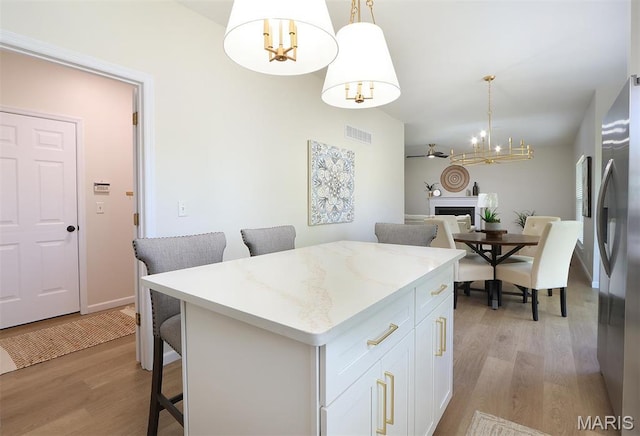 1739 Naughton Way, Swansea, IL 62226 - kitchen with a chandelier, freestanding refrigerator, a kitchen bar, light wood-style flooring, and white cabinets
