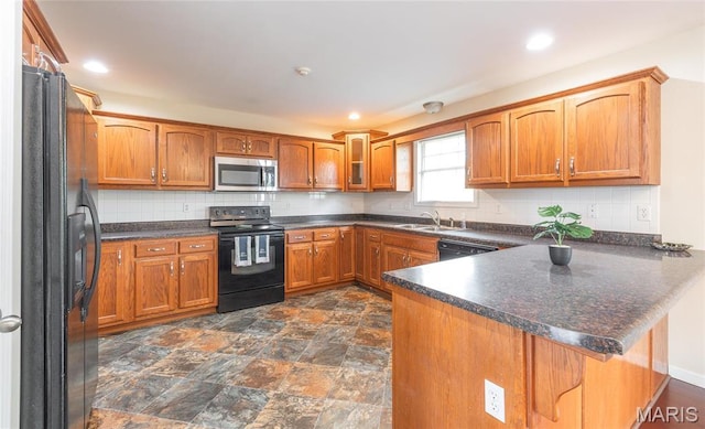 19252 Lambert Ln, Waynesville, MO 65583 - kitchen with black appliances, a peninsula, a sink, brown cabinetry, and decorative backsplash
