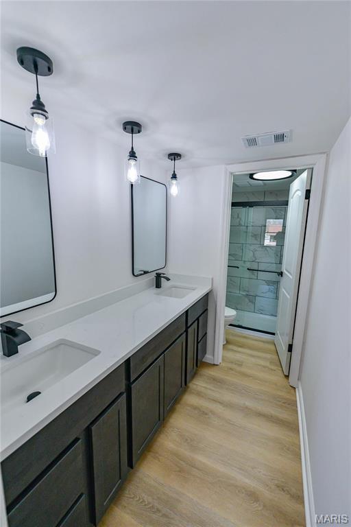 590 Sarah Ln Unit 303, Saint Louis, MO 63141 - bathroom featuring toilet, a shower stall, wood finished floors, double vanity, and baseboards