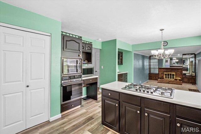 27 Heatherwood Dr, Collinsville, IL 62234 - kitchen with stainless steel appliances, a chandelier, light countertops, dark brown cabinets, and light wood finished floors