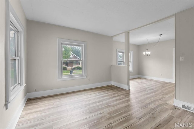 unfurnished room featuring a chandelier, healthy amount of natural light, light wood-type flooring, and baseboards