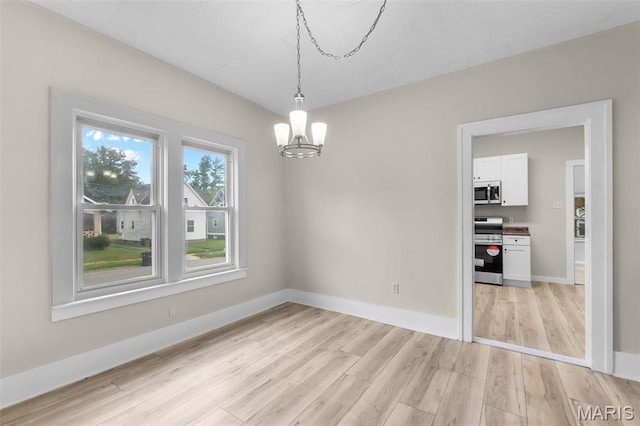 unfurnished dining area with a chandelier, light wood-style floors, and baseboards
