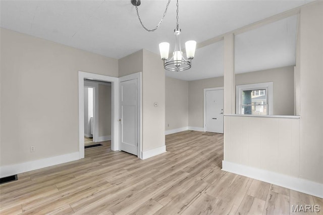unfurnished dining area featuring a chandelier, light wood finished floors, and baseboards