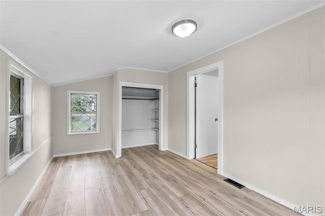 unfurnished bedroom with light wood-style flooring, lofted ceiling, a closet, ornamental molding, and baseboards
