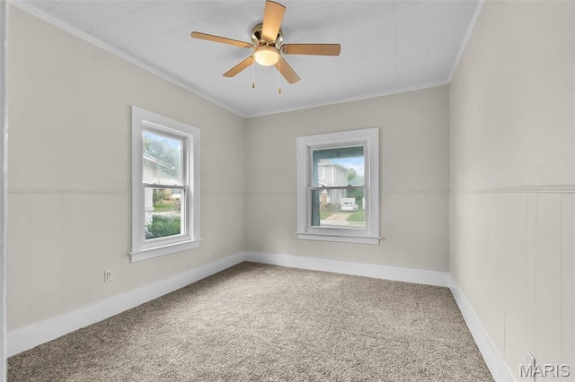 carpeted empty room with ornamental molding, a ceiling fan, and baseboards