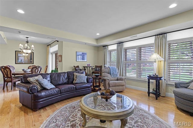 living room featuring a chandelier, light wood-style floors, baseboards, and recessed lighting