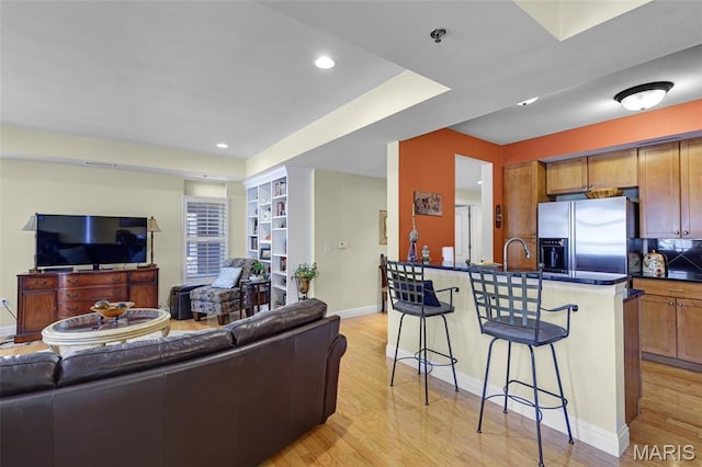 living area with light wood-style flooring, baseboards, and recessed lighting