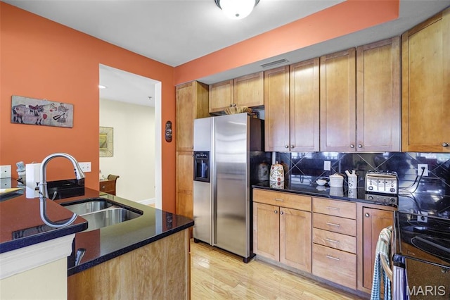 kitchen with stainless steel fridge with ice dispenser, a sink, light wood-style floors, and decorative backsplash