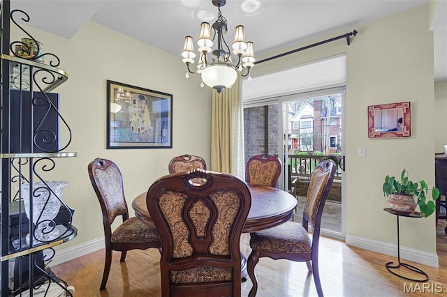dining area featuring a chandelier, baseboards, and wood finished floors