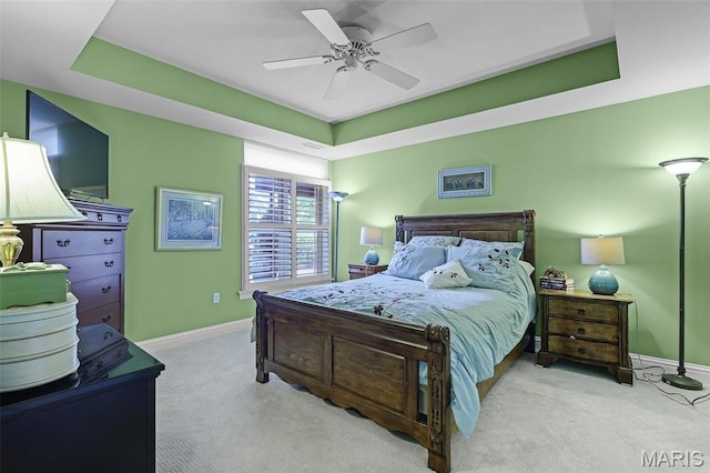 carpeted bedroom with baseboards, a ceiling fan, and a tray ceiling