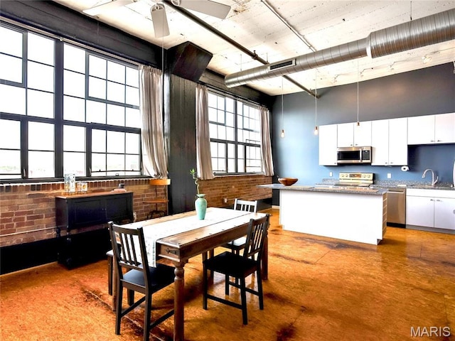 dining area with brick wall, ceiling fan, and a high ceiling