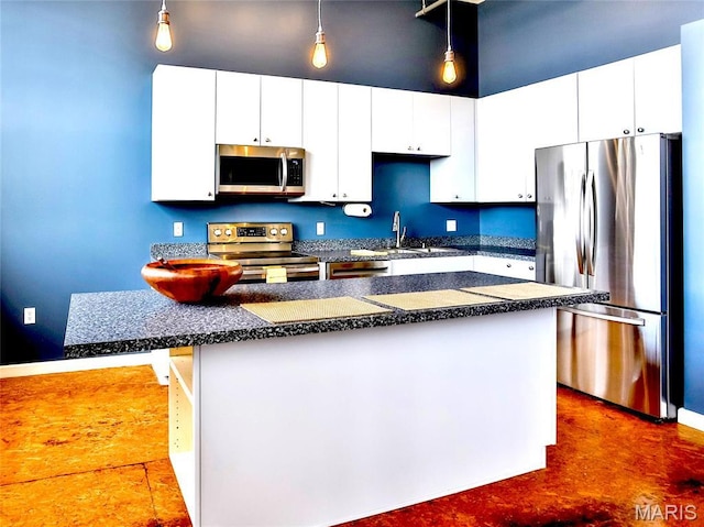 kitchen featuring appliances with stainless steel finishes, dark countertops, hanging light fixtures, and white cabinetry