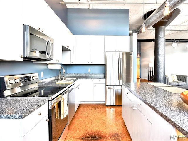 kitchen with appliances with stainless steel finishes, a sink, white cabinetry, and dark countertops
