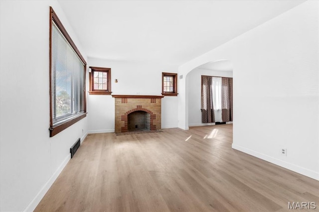 5034 Queens Ave, Saint Louis, MO 63115 - unfurnished living room with arched walkways, light wood-style flooring, and baseboards