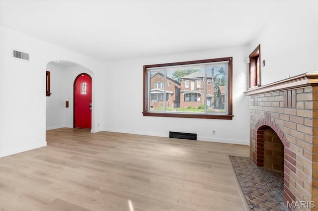 5034 Queens Ave, Saint Louis, MO 63115 - unfurnished living room with light wood-type flooring, arched walkways, baseboards, and a fireplace