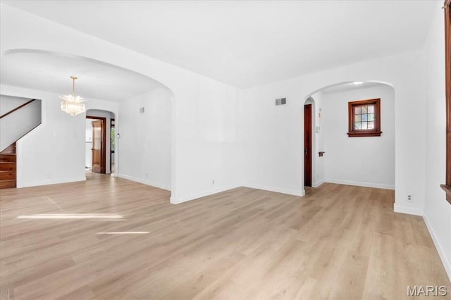 5034 Queens Ave, Saint Louis, MO 63115 - unfurnished living room with light wood-style flooring, arched walkways, stairs, a chandelier, and baseboards