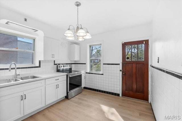 5034 Queens Ave, Saint Louis, MO 63115 - kitchen with stainless steel range with electric cooktop, a sink, tile walls, a wainscoted wall, and healthy amount of natural light