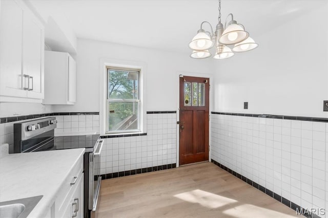 5034 Queens Ave, Saint Louis, MO 63115 - kitchen featuring electric range, tile walls, a chandelier, a wainscoted wall, and white cabinets
