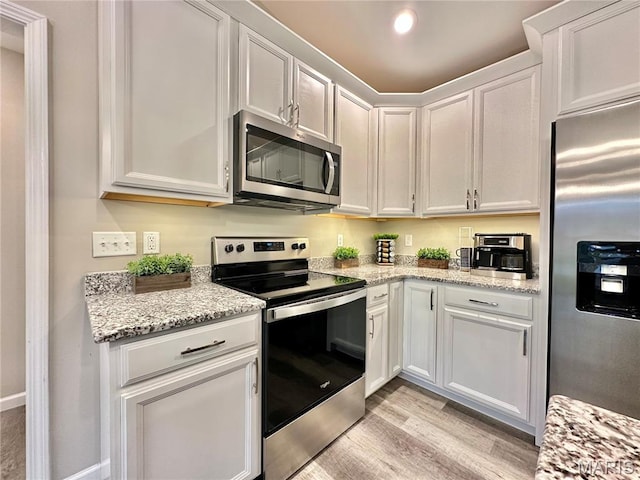 3553 Chippewa Dr, Shiloh, IL 62221 - kitchen featuring appliances with stainless steel finishes, light wood-style floors, white cabinetry, and light stone countertops