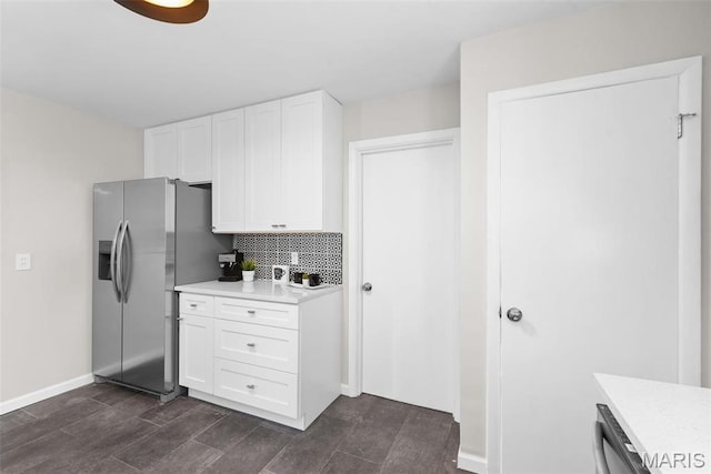 kitchen featuring light countertops, backsplash, white cabinetry, stainless steel fridge with ice dispenser, and baseboards