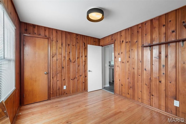 unfurnished bedroom featuring wooden walls and light wood-style flooring