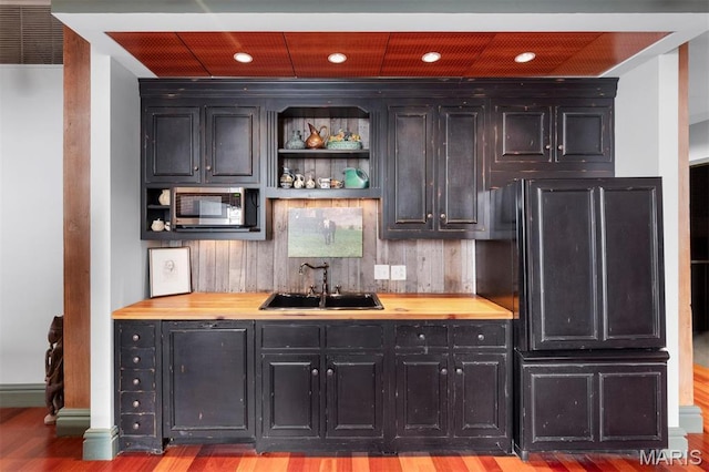 indoor wet bar featuring stainless steel microwave, wood finished floors, fridge, and recessed lighting