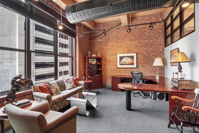 carpeted office space with rail lighting and brick wall
